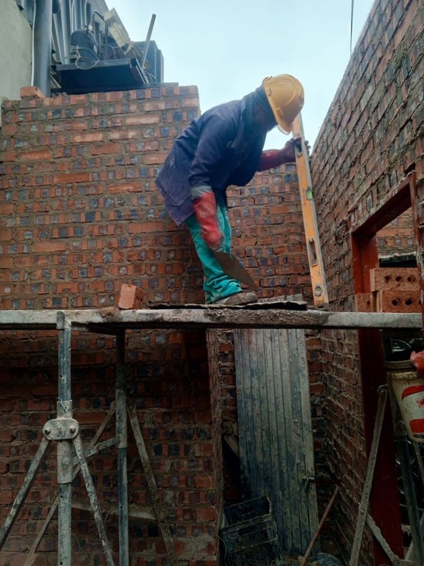 A BlickStone bricklayer checking brickwork against a spirit level during a progress inspection