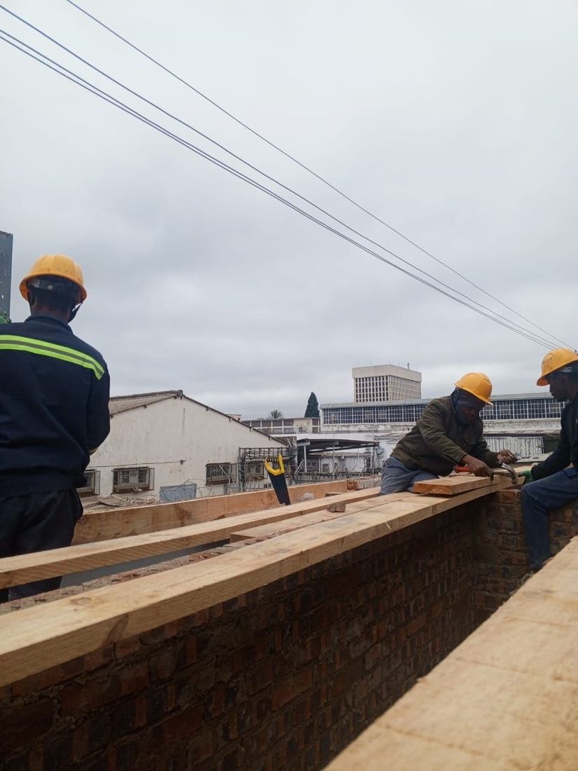 A BlickStone crew laying roof timbers, with the Bulawayo skyline behind them